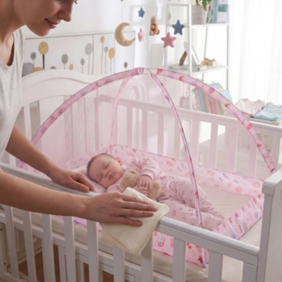 Lit moustiquaire bebe Spot Dôme rose posé sur lit à barreaux avec nouveau-né qui dort