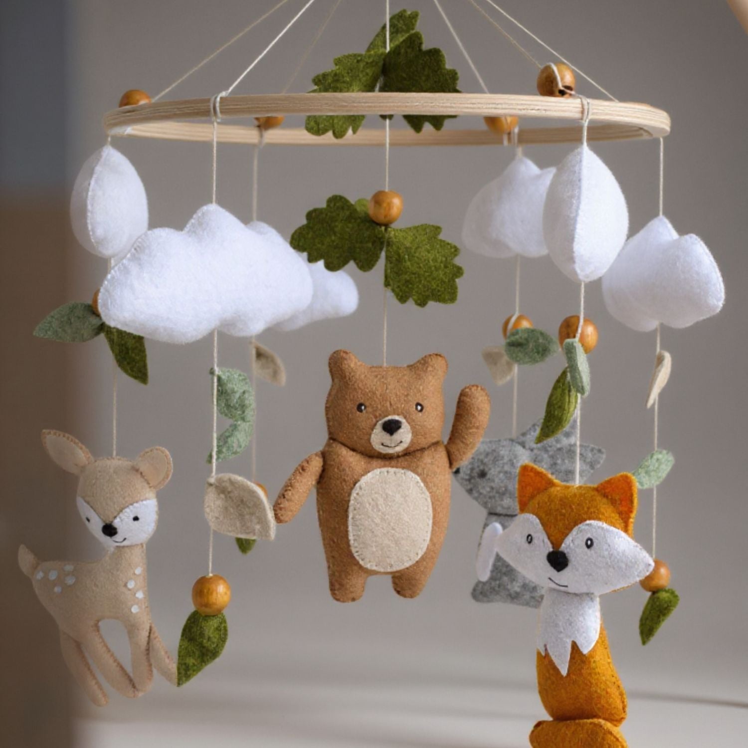 Gros plan des figurines en feutrine (renard, ours, feuillages) du mobile bébé forêt – Spot Bébé