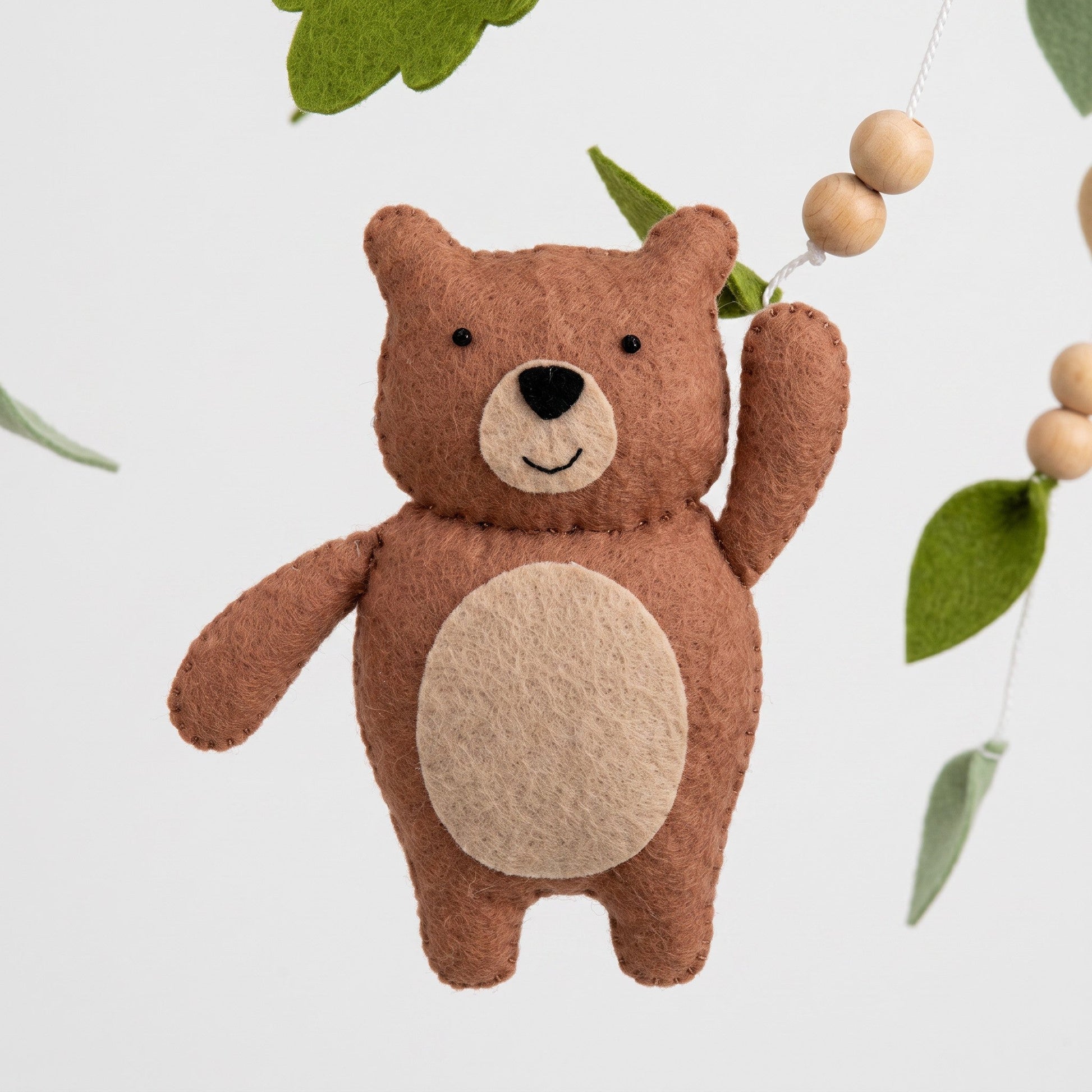 Mobile bébé Animaux de la forêt en feutrine – gros plan sur la figurine ours
Formule avec bras en bois