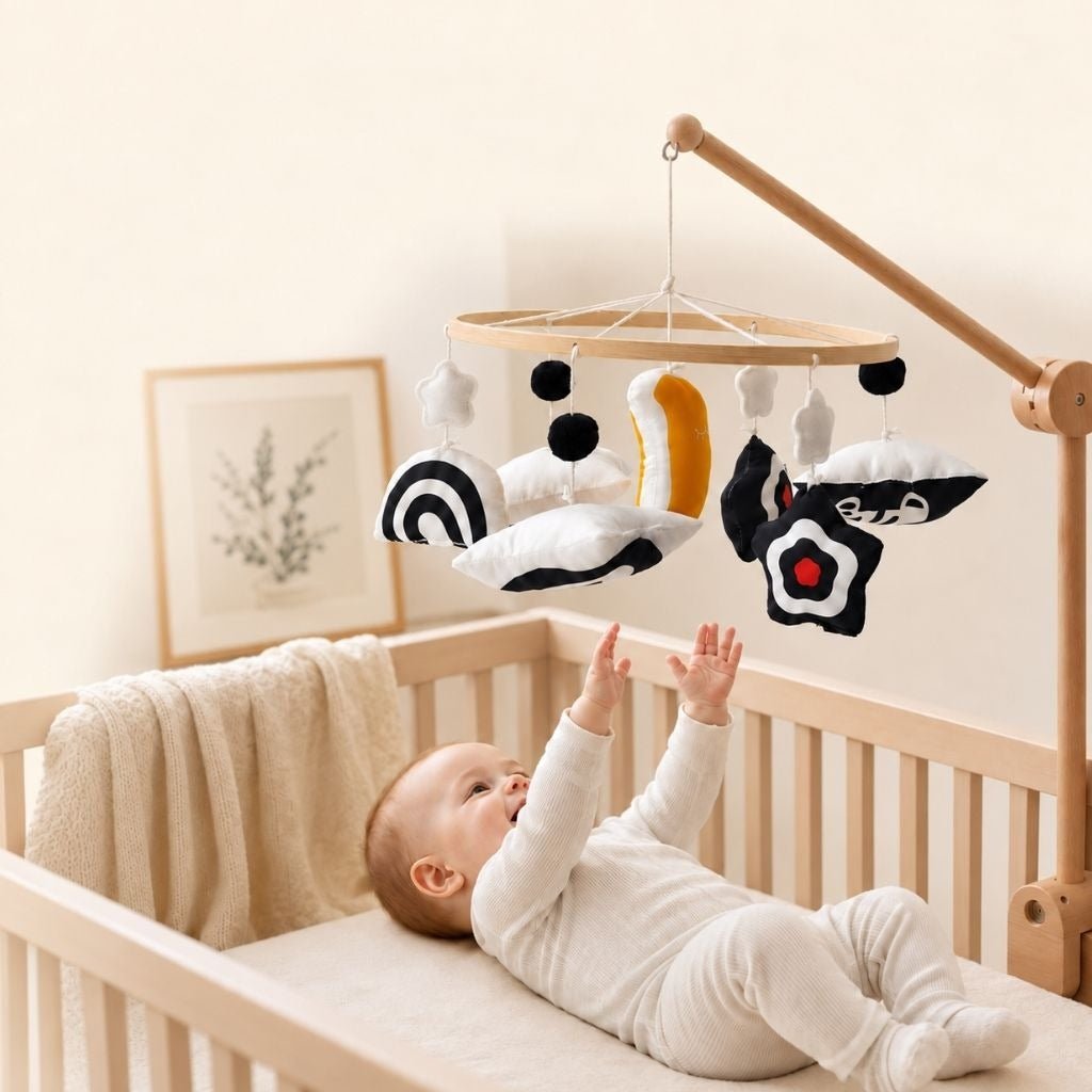 bébé allongé dans son lit qui lève les mains vers le mobile bébé contrasté noir et blanc