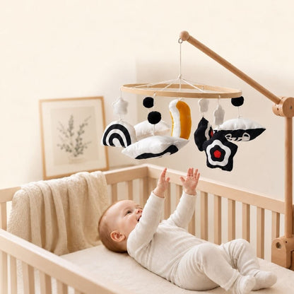 bébé allongé dans son lit qui lève les mains vers le mobile bébé contrasté noir et blanc