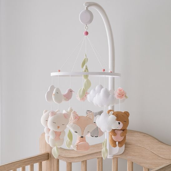 Mobile bébé fille en bois blanc avec figurines en feutrine pastel, installé sur support et équipé d’une cloche musicale pour un rituel apaisant.