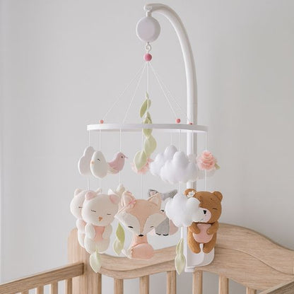 Mobile bébé fille en bois blanc avec figurines en feutrine pastel, installé sur support et équipé d’une cloche musicale pour un rituel apaisant.
