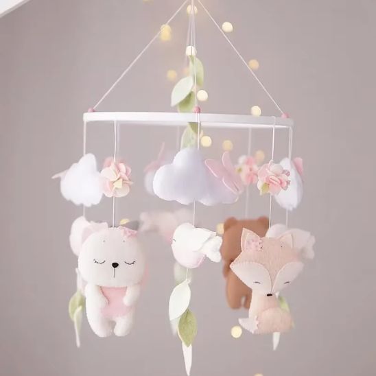 Mobile bébé fille avec figurines lapin et oiseau, tons roses et beige clair.