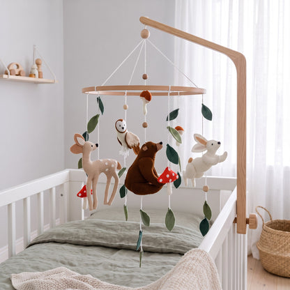 Mobile bébé forêt enchantée suspendu à un bras en bois au-dessus d’un lit bébé blanc