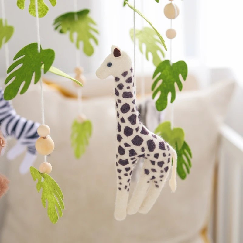 Mobile bébé forêt tropicale détail girafe en feutrine blanche et noire suspendue au-dessus du lit bébé