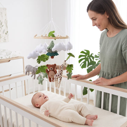 Maman regardant son bébé sous le mobile bébé animaux doux dans son berceau
