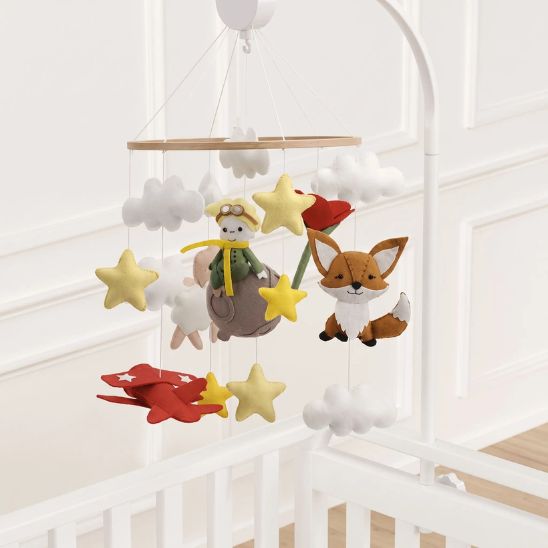 Mobile bébé Petit Prince suspendu à un bras blanc au-dessus du berceau