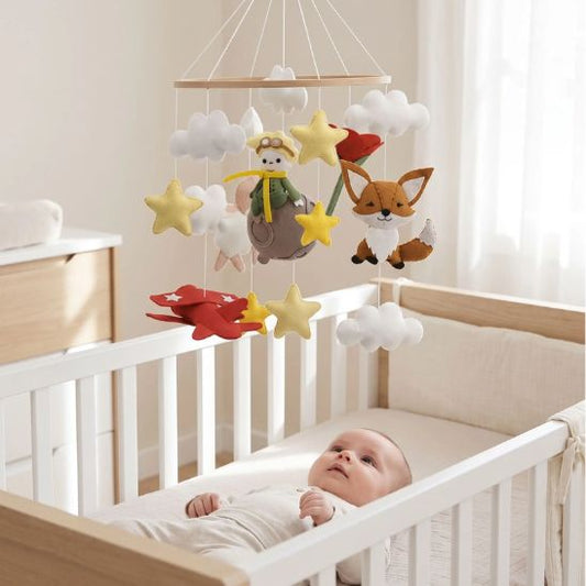 Bébé observe le mobile Petit Prince suspendu au-dessus de son berceau