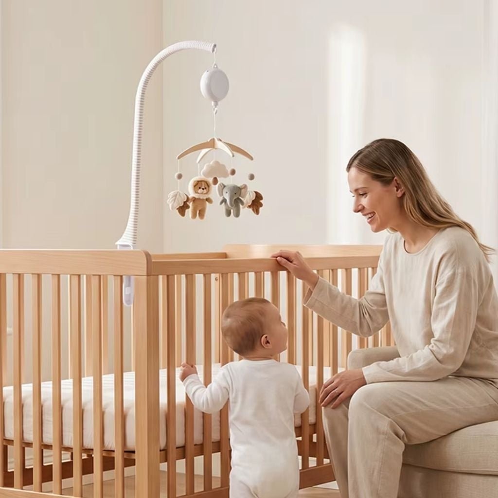maman et bébé debout près du lit qui regardent le mobile musical bébé bohème lion et éléphant