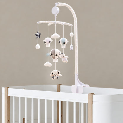 mobile musical bébé sans pile Escale avec montgolfières, ourson et nuages fixé sur un lit blanc et bois