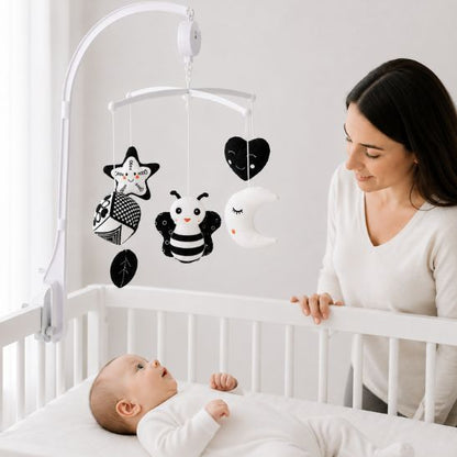 Maman regardant son bébé émerveillé par le mobile musical noir et blanc Montessori