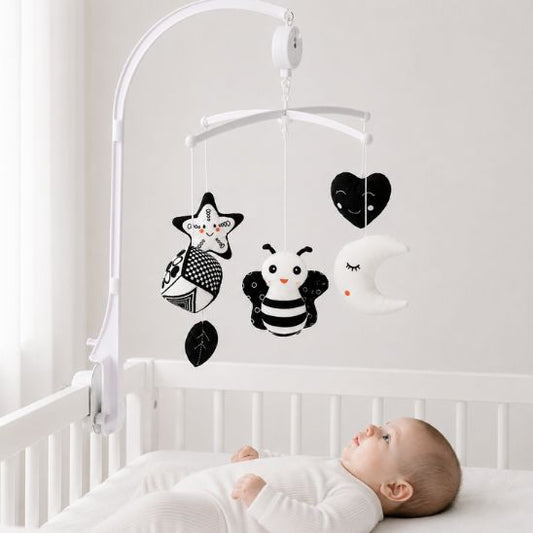 Bébé observant un mobile musical noir et blanc Montessori dans son lit