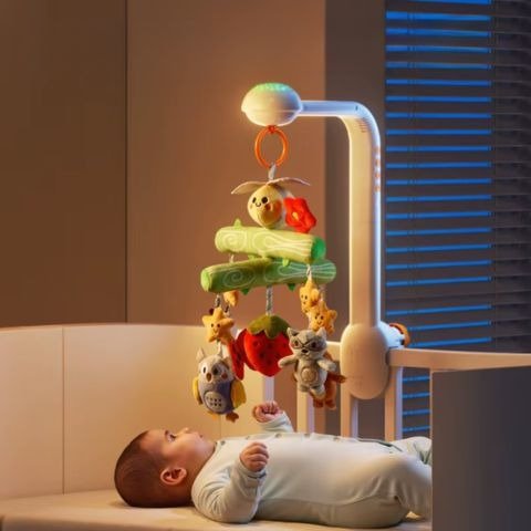 bébé allongé observe son mobile musical avec peluches suspendues