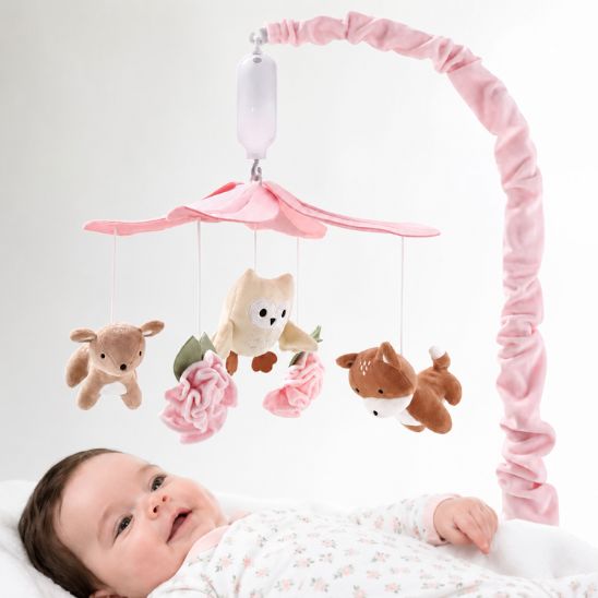 Bébé souriant qui regarde le mobile musical pour bébé forêt féerique dans son lit