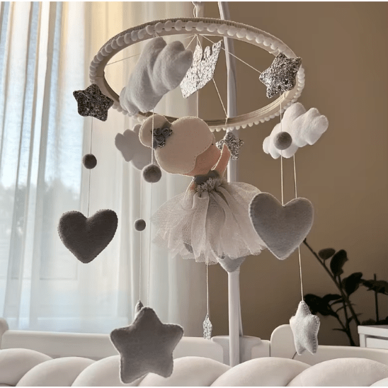 Mobile bébé avec nuages blancs doux, suspendu au-dessus du berceau.