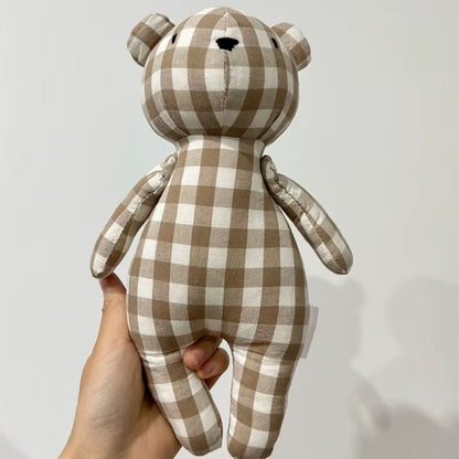 une main tenant l'ourson en peluche en position de face