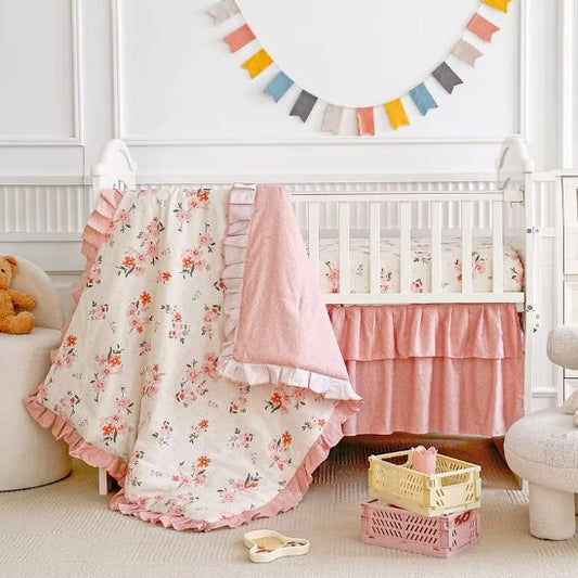 Parure de lit bébé florale posée sur berceau blanc, vue d'ensemble chambre bébé rose et crème