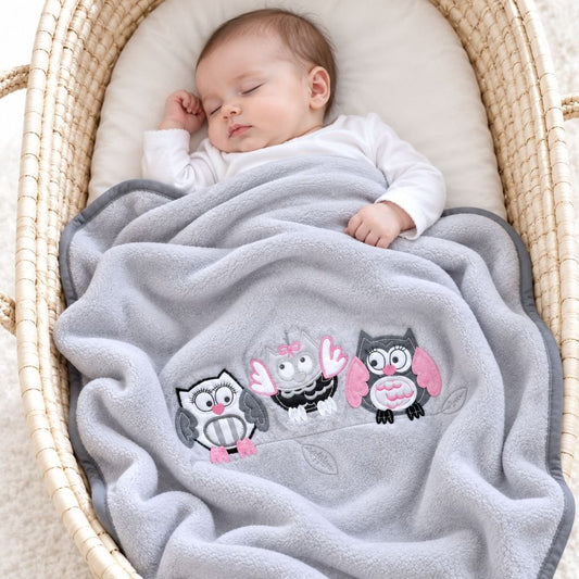 Bébé endormi dans un couffin sous le plaid polaire pour bébé gris