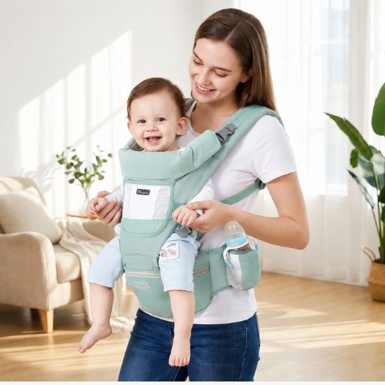 Porte bébé vert menthe avec siège de hanche et porte-biberon – bébé souriant porté face au monde, intérieur lumineux