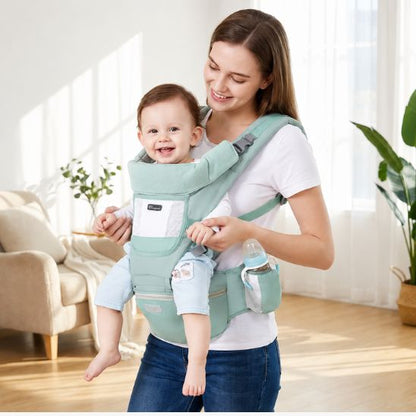 Porte bébé vert menthe avec siège de hanche et porte-biberon – bébé souriant porté face au monde, intérieur lumineux
