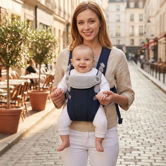 Porte bébé physiologique bleu marine – maman et bébé souriant dans une rue parisienne ensoleillée, terrasse café