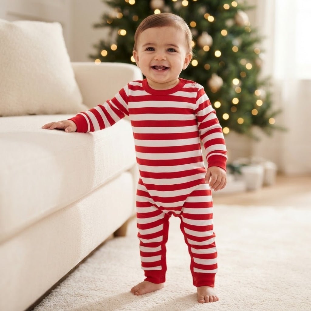 Bébé de 12 mois debout en grenouillère de Noël rayée rouge et blanc à pressions