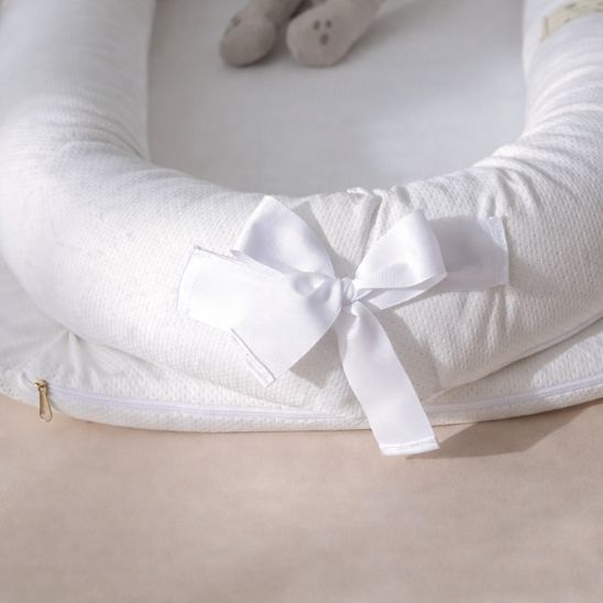 Détail réducteur de lit bébé portable — fermeture éclair housse amovible et nœud satin blanc