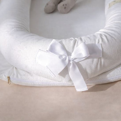 Détail réducteur de lit bébé portable — fermeture éclair housse amovible et nœud satin blanc