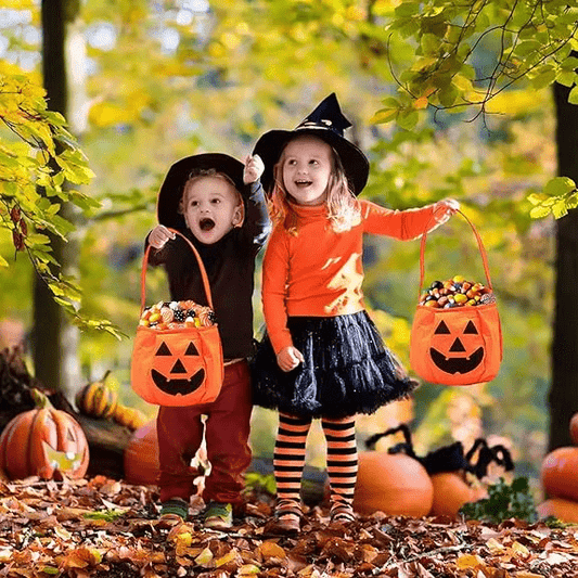 Deux enfants en costume portant un sac Halloween citrouille rempli de friandises – Spot Bébé