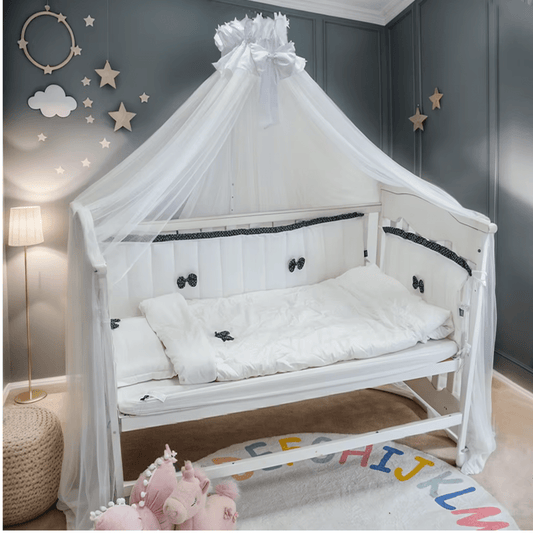 Ensemble complet tour de lit bébé blanc avec nœuds noirs, drap et couverture assortis.