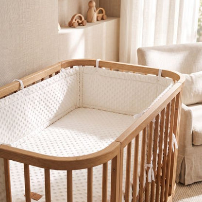 Tour de lit bébé écru à pois en relief installé dans un berceau en bois