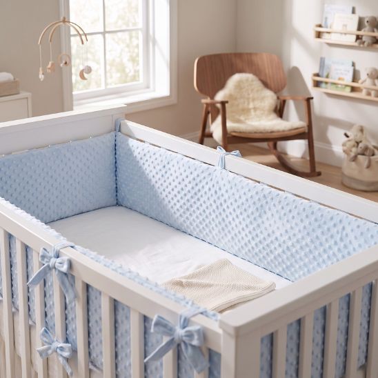 Tour de lit bébé bleu à pois en relief installé dans un berceau blanc
