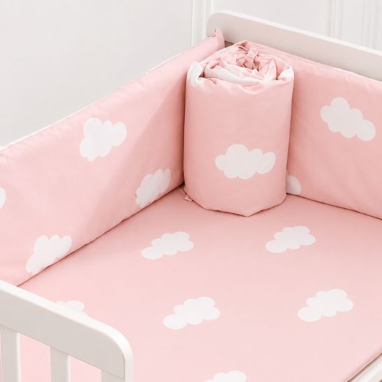Tour de lit bébé fille nuage rose pastel roulé posé dans berceau blanc
