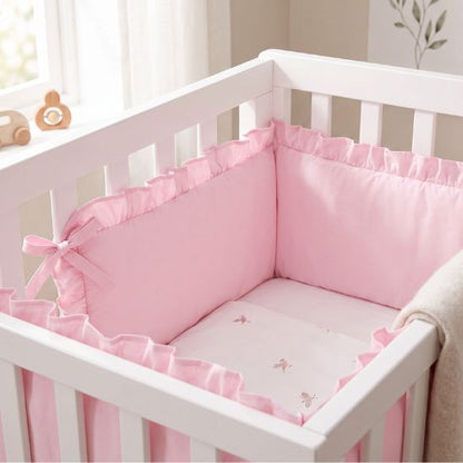 Tour de lit bébé rose à volant fixé aux barreaux du berceau
