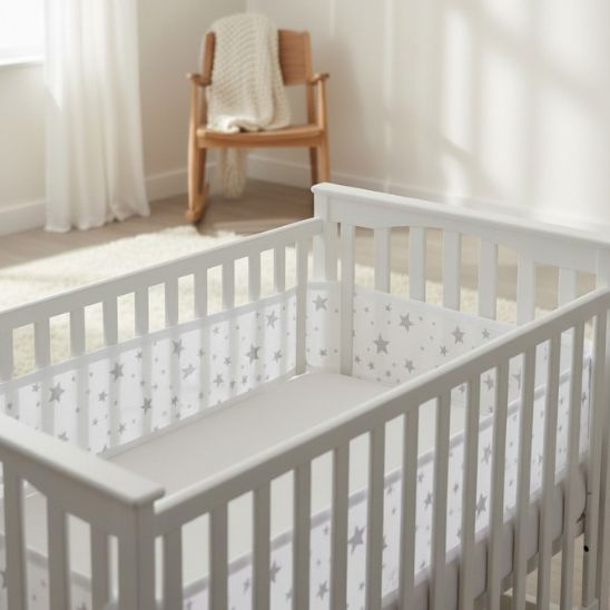Tour de lit respirant étoiles grises installé dans lit à barreaux blanc chambre bébé