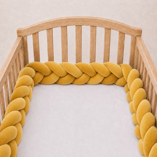 Tresse de lit bébé moutarde installée le long d'un lit à barreaux
