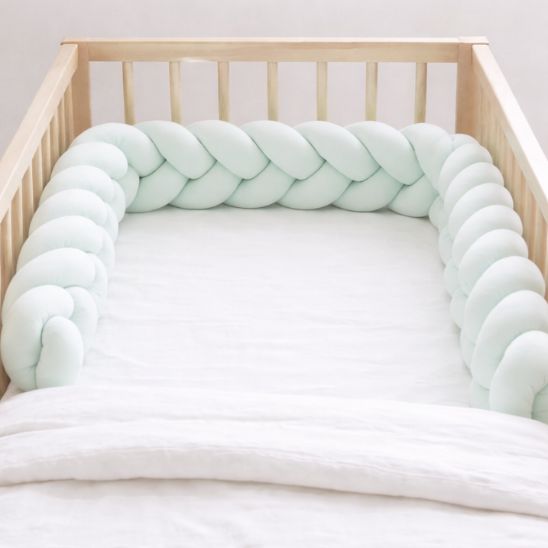 Tresse de lit bébé tressée vert d'eau installée en forme U dans berceau bébé