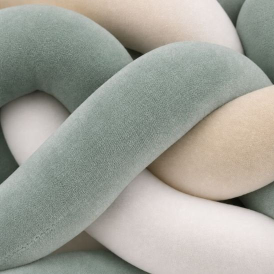 Macro sur la texture veloutée d'une tresse de lit bébé vert sauge, beige et blanc