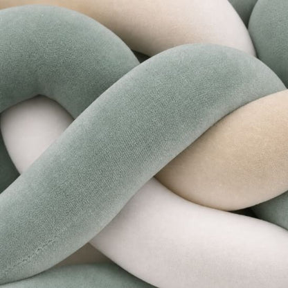 Macro sur la texture veloutée d'une tresse de lit bébé vert sauge, beige et blanc