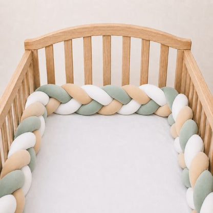 Tresse de lit vert sauge, beige et blanc installée le long des barreaux d'un lit en bois clair