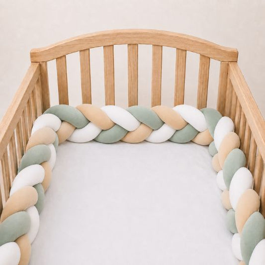 Tresse de lit vert sauge, beige et blanc installée le long des barreaux d'un lit en bois clair