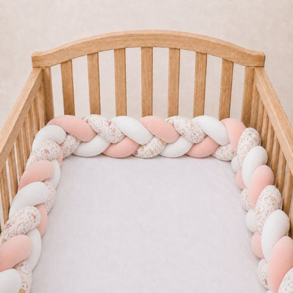 Tresse de lit Doudou rose et blanche installée le long d'un lit à barreaux