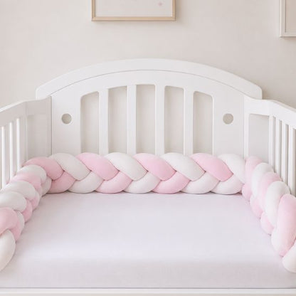 Tresse de lit rose et blanc installée tout le long d'un lit à barreaux bébé