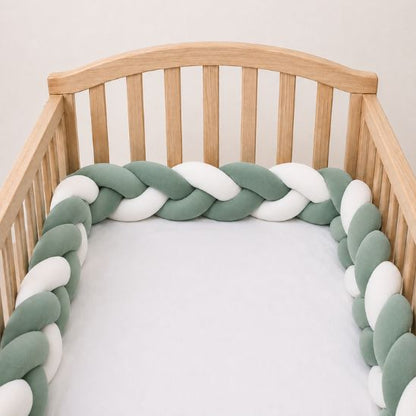Tresse de lit bébé vert sauge et blanc installée sur un lit à barreaux en bois