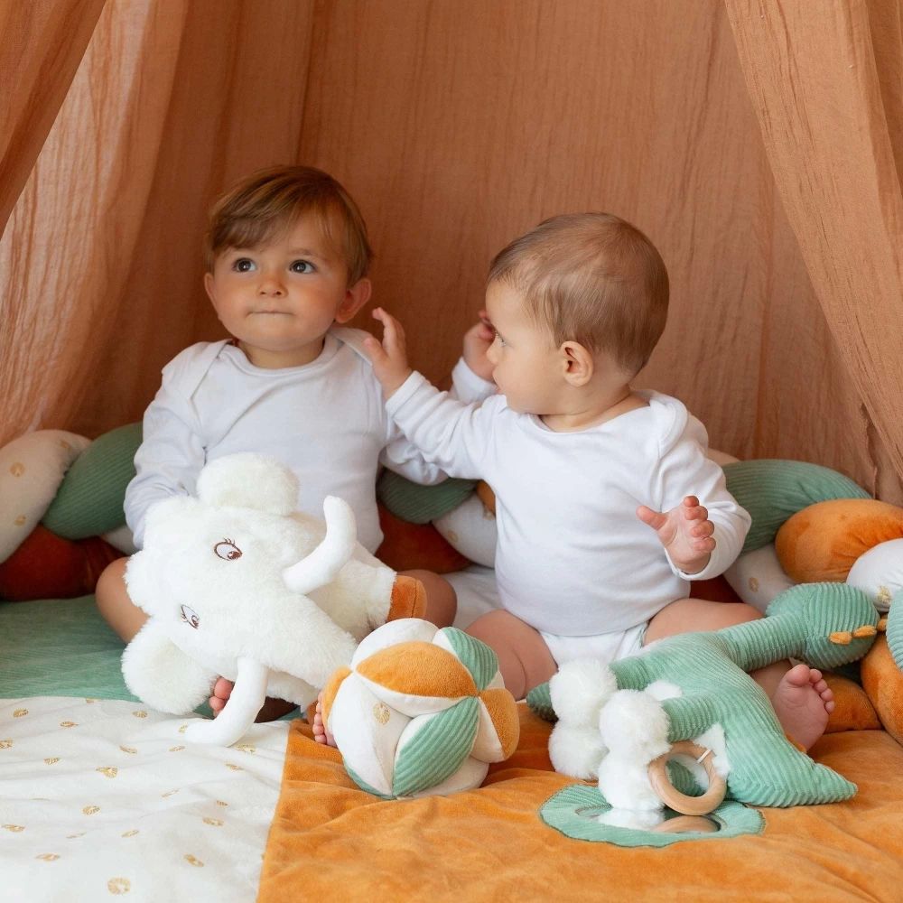 Tour de lit tressé bébé 3 brins vert sauge et camel décoré avec jouets dans un berceau.
