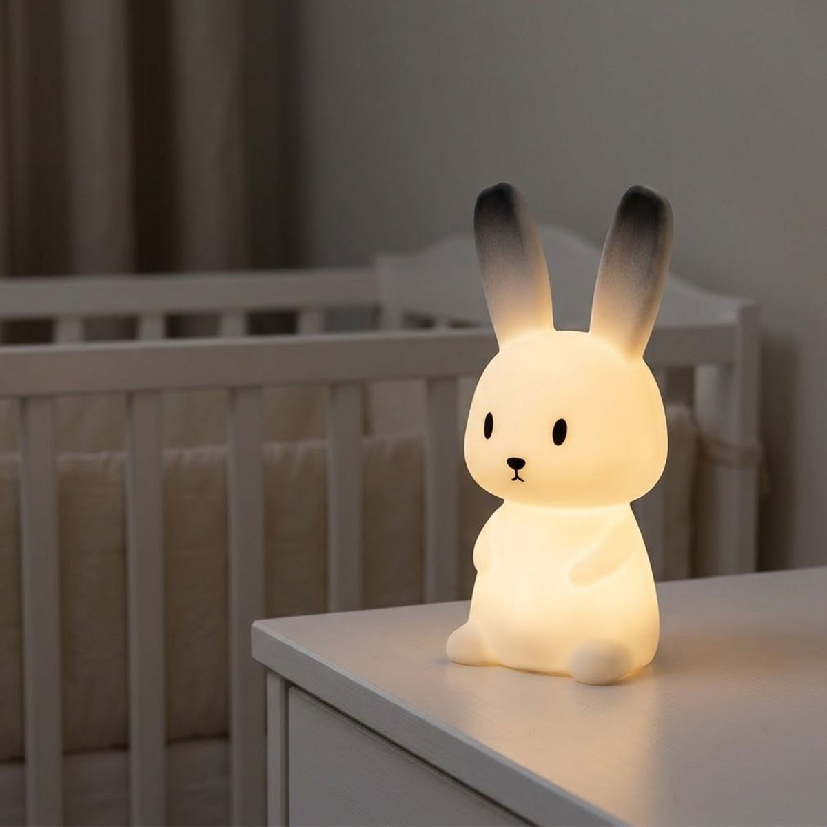 Veilleuse bébé lapin en silicone allumée sur une commode près du lit de bébé