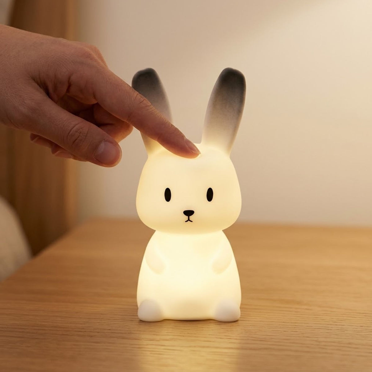 Doigt qui tapote la tête de la veilleuse bébé lapin pour l'allumer