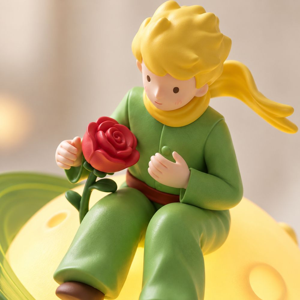 Gros plan de la figurine Le Petit Prince tenant sa rose sur la planète lumineuse