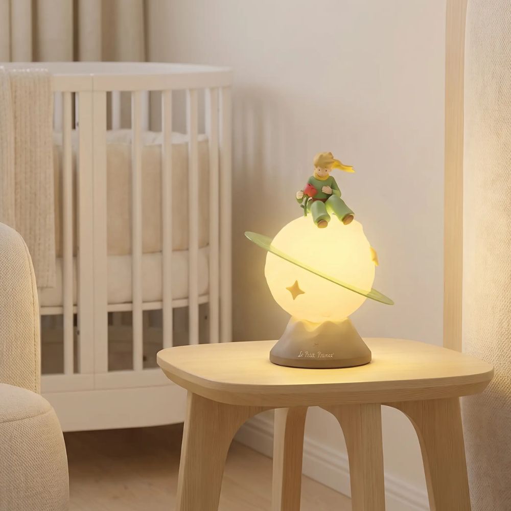Veilleuse bébé Le Petit Prince lumineuse sur une table près du lit de bébé